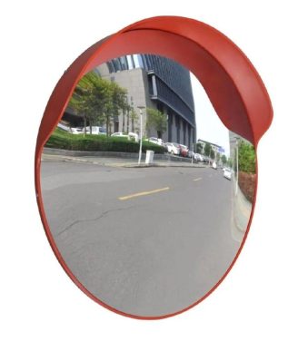 The Warrior 60CM Convex Mirror WAR-CM60-PM, resembling a warrior's shield, reflects the surrounding scenery as a vibrant red circle on the side of the road.